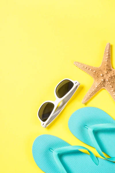 Blå flip flops, solglasögon och sjöstjärnor på gula ovanifrån. — Stockfoto