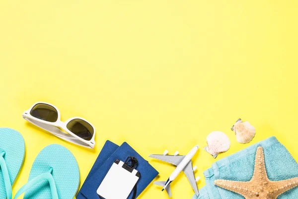 Chanclas azules, gafas de sol, pasaporte, avión y estrellas de mar sobre fondo amarillo . — Foto de Stock