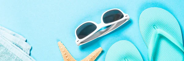 Blauwe slippers, zonnebril en zeester op blauwe achtergrond. — Stockfoto