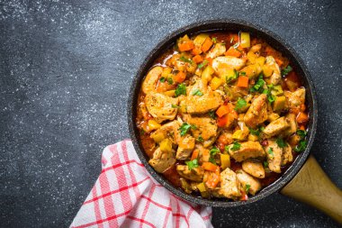 Tavuk güveç sebze siyah taş tabloyla, üstten görünüm.