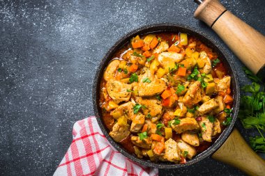 Tavuk güveç sebze siyah taş tabloyla, üstten görünüm.