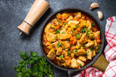 Tavuk güveç sebze siyah taş tabloyla, üstten görünüm.