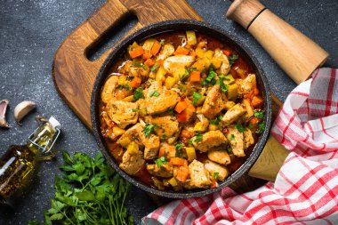 Tavuk güveç sebze siyah taş tabloyla, üstten görünüm.