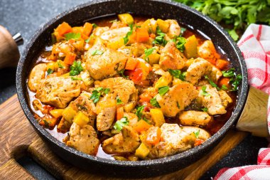 Tavuk güveç sebze siyah taş tabloyla, üstten görünüm.