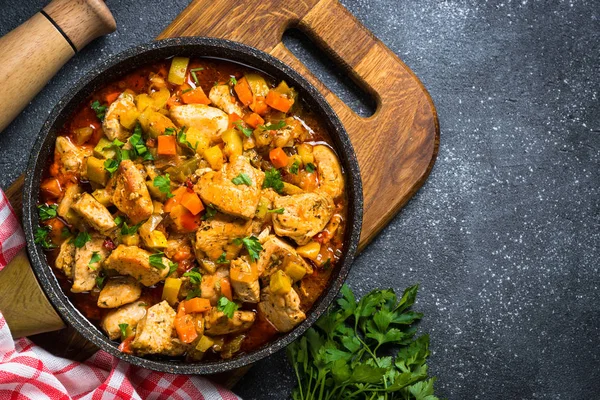 Chicken stew with vegetables black stone table, top view. — Stock Photo, Image