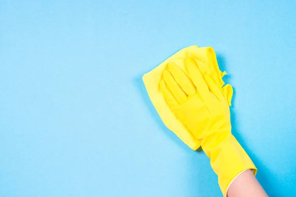 Mão em luvas amarelas e microfibra pano de limpeza fundo azul . — Fotografia de Stock