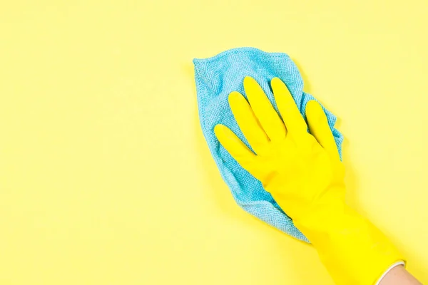 Mano en guantes amarillos y trapo de microfibra limpieza fondo amarillo . — Foto de Stock