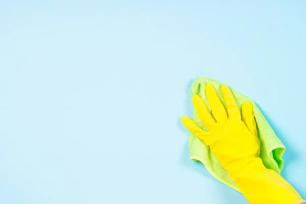 Mano in guanti gialli e microfibra straccio pulizia sfondo blu . — Foto Stock