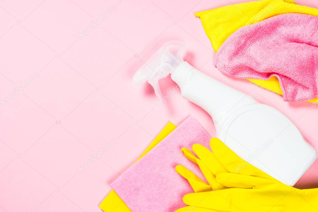 Cleaning spray, cloth and gloves on pink background.