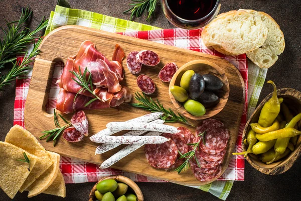 Antipasto - нарізане м'ясо, шинка, салямі, оливки на темному кам'яному столі вид зверху . — стокове фото