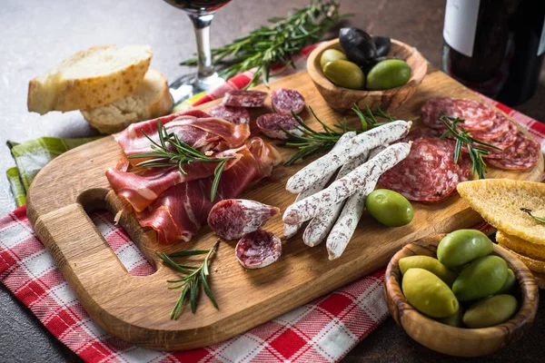 Антипасто делікатеси - нарізане м'ясо, шинка, салямі, оливки на дерев'яній дошці . — стокове фото