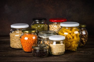 Cereals, Legumes, and beans in glass jars on  kitchen table.  clipart