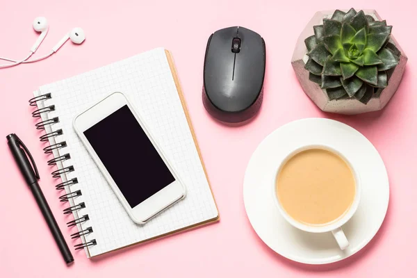 Posto di lavoro freelance con blocco note, tazza di caffè, succulento e mouse su rosa — Foto Stock