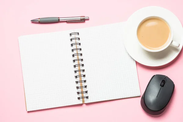 Posto di lavoro ufficio con blocco note, tazza di caffè e mouse sulla scrivania rosa . — Foto Stock