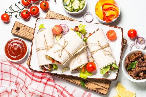 Burritos tortilla enveloppe de boeuf et légumes sur blanc . — Photo