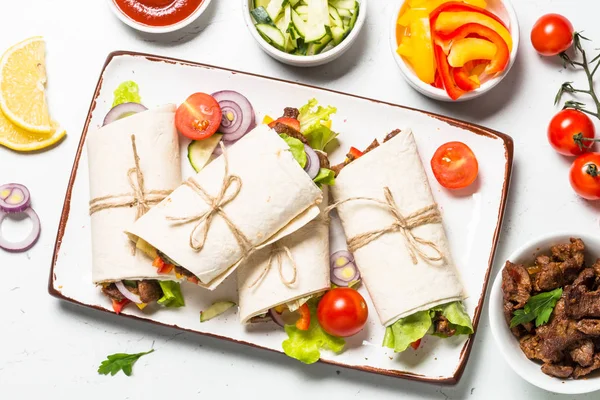 Burritos tortilla wraps med nötkött och grönsaker på vit. — Stockfoto