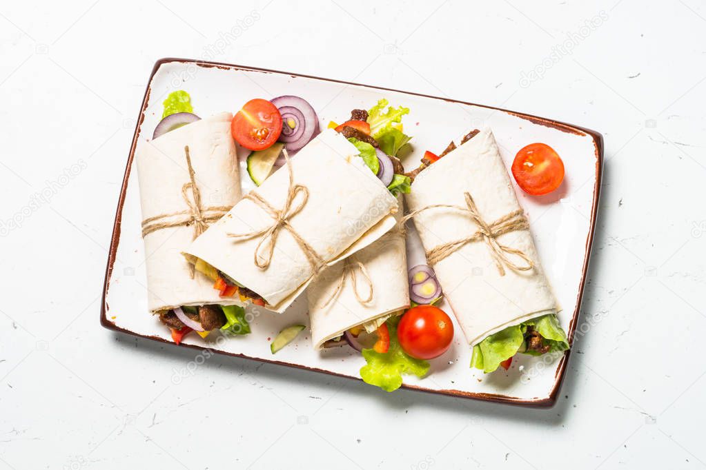 Burritos tortilla wraps with beef and vegetables on white.