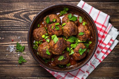 Ahşap masa üstüne domates soslu köfte görüntülemek. 