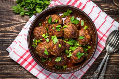 Ahşap masa üstüne domates soslu köfte görüntülemek. 