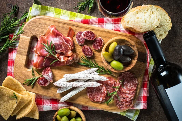 Antipasti - nakrájené maso, šunka, salám, olivy na pohled shora tmavě kamenný stůl. — Stock fotografie