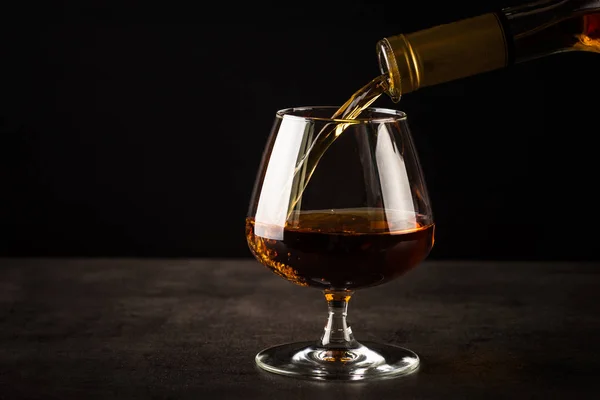 Brandewijn of cognac in het glas gieten. — Stockfoto