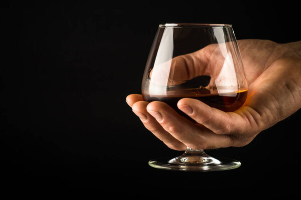 Man hold Cognac or brandy glass in his hand.