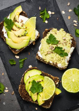 Siyah üzerinde avokado ile sandviçler.