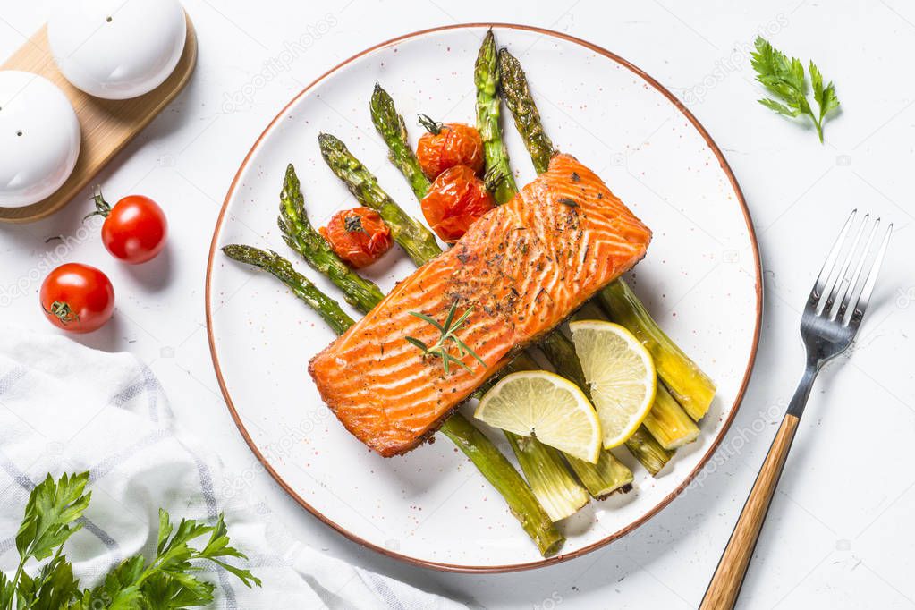 Grilled salmon fish fillet with asparagus on white. 