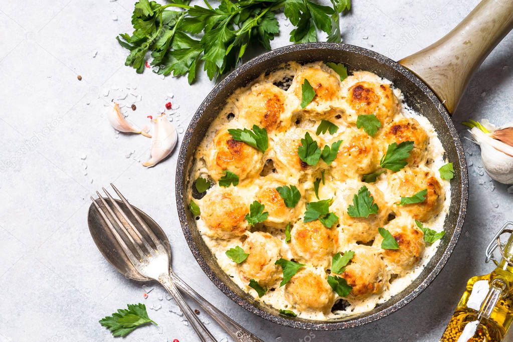 Meatballs in cream sauce with cheese and herbs top view.