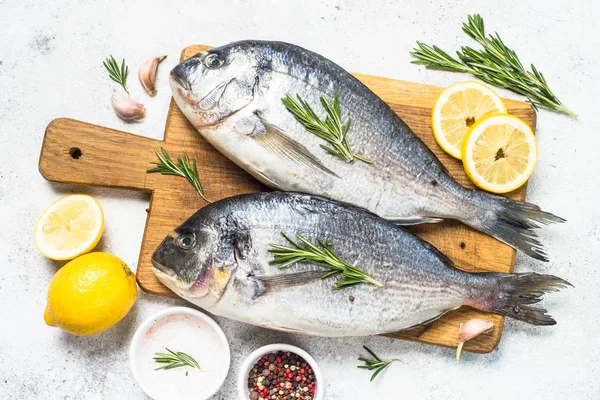 Peixe dorado cru sobre tábua de corte na mesa . — Fotografia de Stock