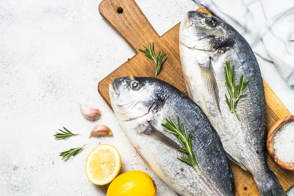 Poisson dorado cru sur la planche à découper sur la table . — Photo