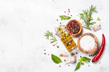 Baharatlar, otlar ve zeytinyağı beyaz taş tablo üzerinde.