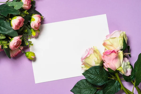 Folha de papel vazia e flores em um fundo roxo . — Fotografia de Stock