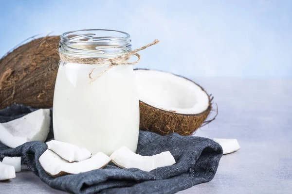 Leite de coco em frasco de vidro no fundo azul . — Fotografia de Stock