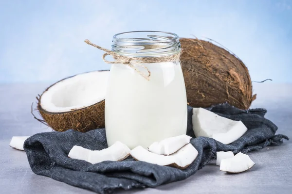 Leite de coco em frasco de vidro no fundo azul . — Fotografia de Stock