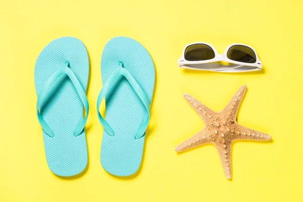 Blå flip flops, solglasögon och sjöstjärnor på gul bakgrund. — Stockfoto