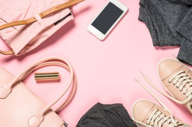 Pembe arka planda kadın giysisi ve aksesuarları.