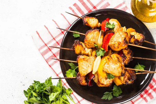 Chicken kebab with vegetables on skewers on white.