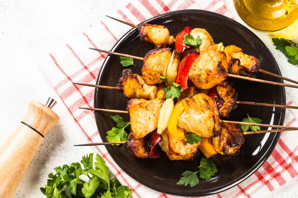 Chicken kebab with vegetables on skewers on white.