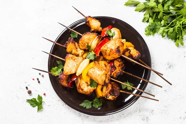 Chicken kebab with vegetables on skewers on white.