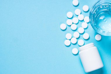 Pills ve cam su mavi üstte görünümü.