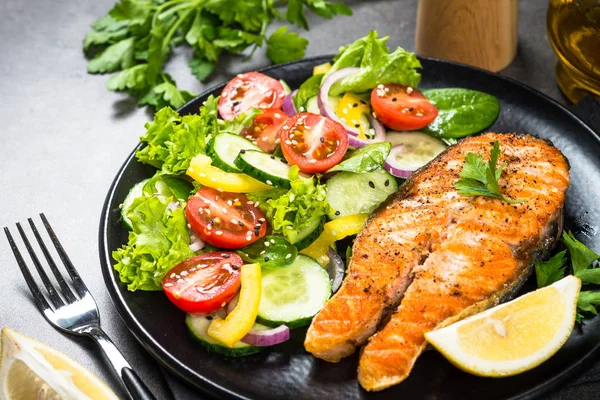 Grilled salmon fish steak with vegetables on black. — Stock Photo, Image