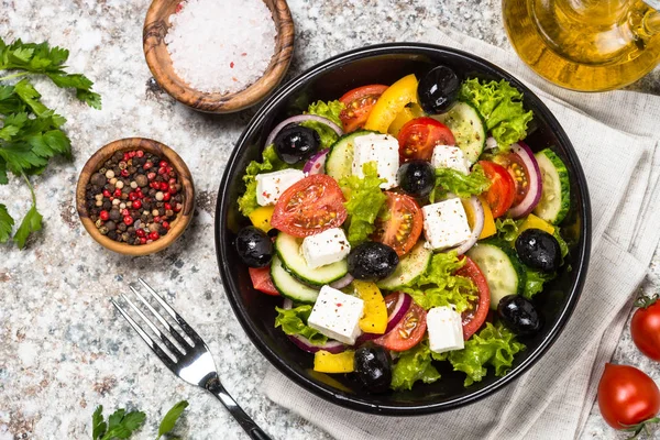 Грецький салат в чорному тарілку на столі. — стокове фото