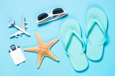 Mavi flip flop, güneş gözlüğü ve denizyıldızı mavi zemin üzerine.