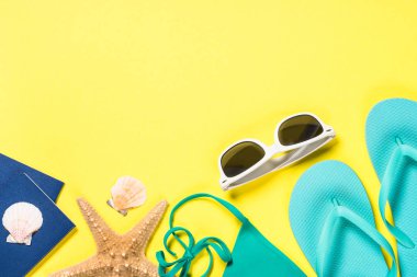 Mavi flip flop, Mayo, güneş gözlüğü ve Sarı zemin üzerine deniz yıldızı.