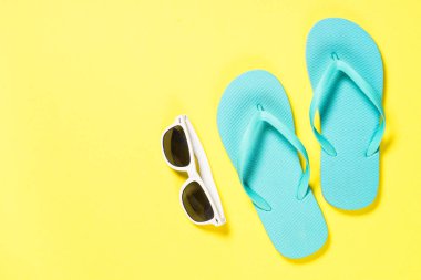 Mavi flip flop, Mayo, güneş gözlüğü ve Sarı zemin üzerine deniz yıldızı.