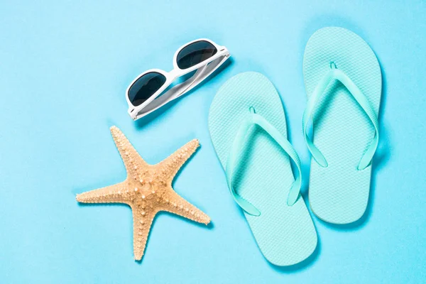 Blå flip flops, solglasögon och sjöstjärnor på blå bakgrund. — Stockfoto