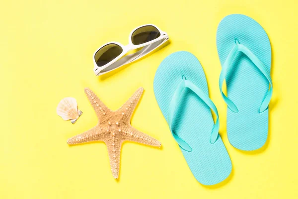 Blå flip flops, badkläder, solglasögon och sjöstjärnor på gul bakgrund. — Stockfoto