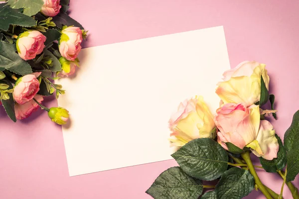 Folha de papel vazia e flores no fundo rosa . — Fotografia de Stock