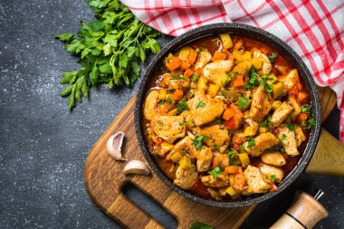 Tavuk güveç sebze siyah taş tabloyla, üstten görünüm.